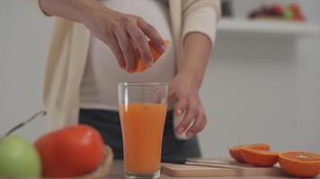 A pregnant woman is juicing orange juice to add vitamins to her unborn child. Women make their own orange juice by buying the orange and squeeze the juice. Healthy person. video