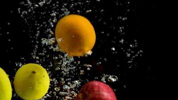 A variety of fruits fall into the water in a clear glass aquarium and air bubbles rise to the surface of the water. video