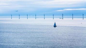 airplane, ships and bridge near offshore wind farm photo