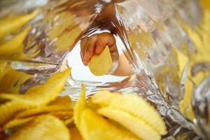 Hand hold potato chips inside snack foil bag photo