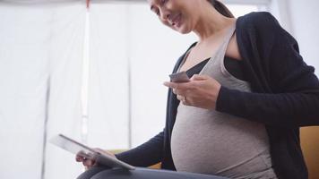 Asian pregnant woman using tablet to consult online with obstetrician video