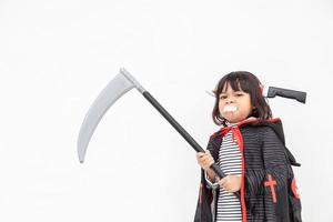 Children girl wearing mysterious Halloween dress holding a sickle on white background photo