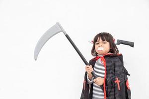 Children girl wearing mysterious Halloween dress holding a sickle on white background photo