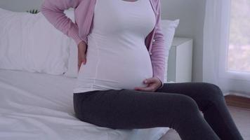 Pregnant women gently pat stomach with hands. Pregnant women are feeling uncomfortable and have back pain due to weight gain as a result of increasing gestational age. Concept Symptoms of pregnant. video