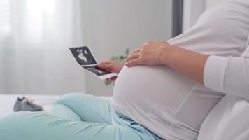 pregnant woman is bubbling gently to show love for her unborn child and pick up film ultrasound to determine the sex of her child. ultrasound system helps to monitor the growth of the unborn child. video