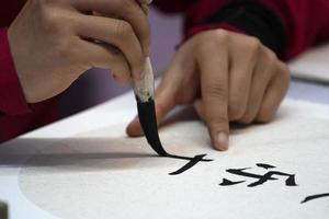 japanese woman writing name Charles in ideograms with brush photo