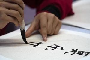 japanese woman writing name Charles in ideograms with brush photo