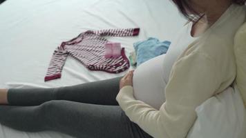 Mother is folding baby clothes to prepare for the upcoming baby. A pregnant woman is checking necessary for newborn. Concept prepare of pregnancy readiness for mothers. video