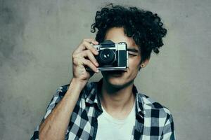 guy with a camera in his hands on a gray background indoors hobby plaid shirt model photo