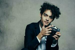 curly-haired man in a classic suit looks at the camera in his hand studio hobby photo