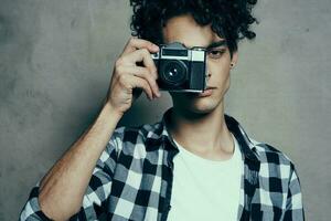 handsome guy with a camera near his face and curly hair plaid shirt hobby photographer photo