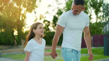 papá y hija caminar alrededor su zona a puesta de sol. niño sostiene del padre mano video