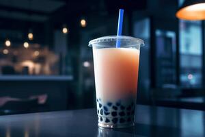 Refreshing drink bubble tea in a plastic cup with a straw in a cafe on a table, close-up. photo