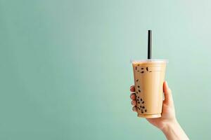 A hand holding takeaway plastic cup of delicious iced bubble milk tea and black pearls with copy space. ai generated photo