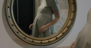 Pregnant woman looking at mirror and stroking belly video