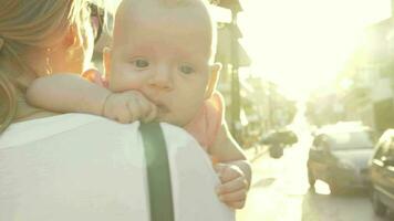 Mum with baby walking outside against bright sun flare video