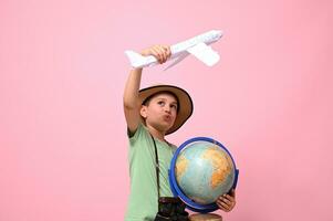 A cute boy holds a globe and an airplane in his hands, simulating a flight around the globe. Travel concept. photo