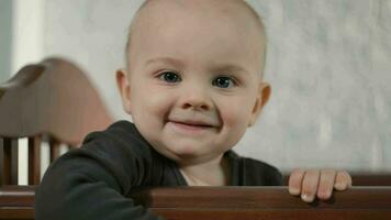 Portrait of happy toddler boy standing in baby crib. video