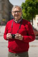 Senior man tourist enjoys photographing at the city photo