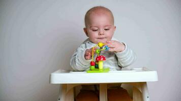 Cute infant baby sitting in high chair playing with developing toys. video