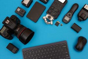 Top View of Photographer's, Videographer's or Video Blogger's Workplace. Digital Gadgets Lying on Blue Table Flat Lay photo