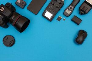 Top View of Photographer's, Videographer's or Video Blogger's Workplace. Digital Gadgets Lying on Blue Table Flat Lay photo