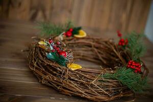 Christmas wreath on a wooden background. Christmas wreath made of twigs, berries and oranges. photo