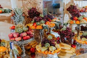 Wedding decorations. Reception. Buffet. Fruits and cheese on plates with bread in boxes. Food bar decorated by flowers and lanters photo