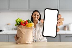 Happy young indian woman order grocery online, showing smartphone photo