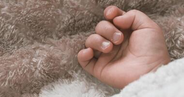 A right hand of sleeping asian baby on the carpet handheld video