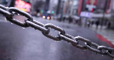 A silver chain behind walking people at the SHIBUYA crossing rainy day video