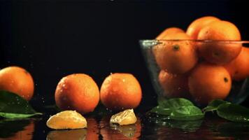 Pieces of ripe tangerines fall on the table with splashes of water. On a black background. Filmed is slow motion 1000 frames per second. video