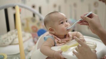 A baby is being fed by a person. The baby is eating from a spoon video