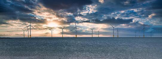 Offshore Wind Turbine in a Windfarm under construction off the England Coast at sunset photo