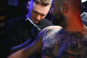 tattoo artist demonstrates the process of getting black tattoo with paint. Master works in black sterile gloves photo