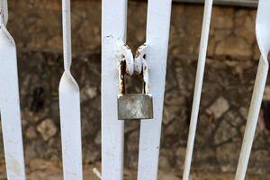 An old metal lock hangs on the fence. photo