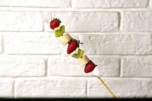 Fruit Skewer Against White Brick Wall photo