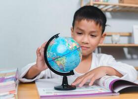 Kid Education, Asian boy looking at globe find the location of countries in the world, Concept for research global warming, global network, SEO search engine, Save the Earth, Ecology. photo