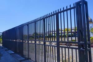 A black iron fence that stands firmly in the sunlight photo