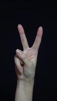 Close-up of hand showing victory sign. Isolated on black background. video