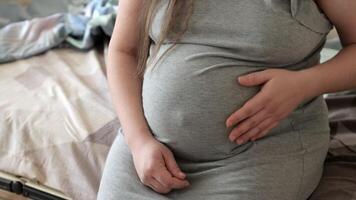 Close-up of a pregnant woman gently touching her belly before childbirth. The image captures the emotional connection and anticipation, highlighting the intimate and comforting moments before delivery video