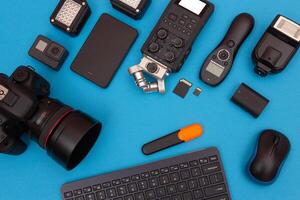 Top View of Photographer's, Videographer's or Blogger's Workplace. Digital Gadgets Lying on Blue Table - Flat Lay photo