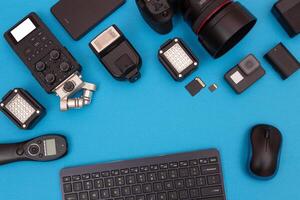 Top View of Photographer's, Videographer's or Blogger's Workplace. Digital Gadgets Lying on Blue Table - Flat Lay photo