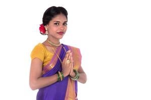 Young Indian girl in traditional clothing greeting namaste, Welcome, Indian girl in a tradition sari with welcome expression inviting photo