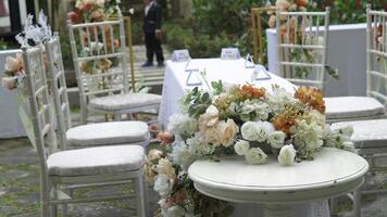 Fancy wedding reception table setting with flower arrangements on top and outdoor background. video