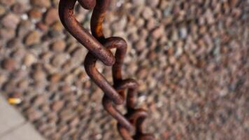 Weathered rusty metal chain over blurry pebble garden path video