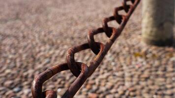 Weathered rusty old chain over blurry pebble garden pathway video