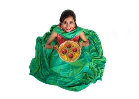 Portrait of a Indian Traditional Girl holding Diya, Girl Celebrating Diwali or Deepavali with holding oil lamp during festival of light on white background photo