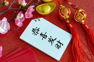 Top view of Chinese New Year saying Gong Xi Fa Cai on white notepad with Chinese New Year decoration background photo