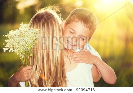 Mother and her little son with bouquet of flowers outdoors, Happy family mom and kid kissing and hugging. Mother's day gift. 